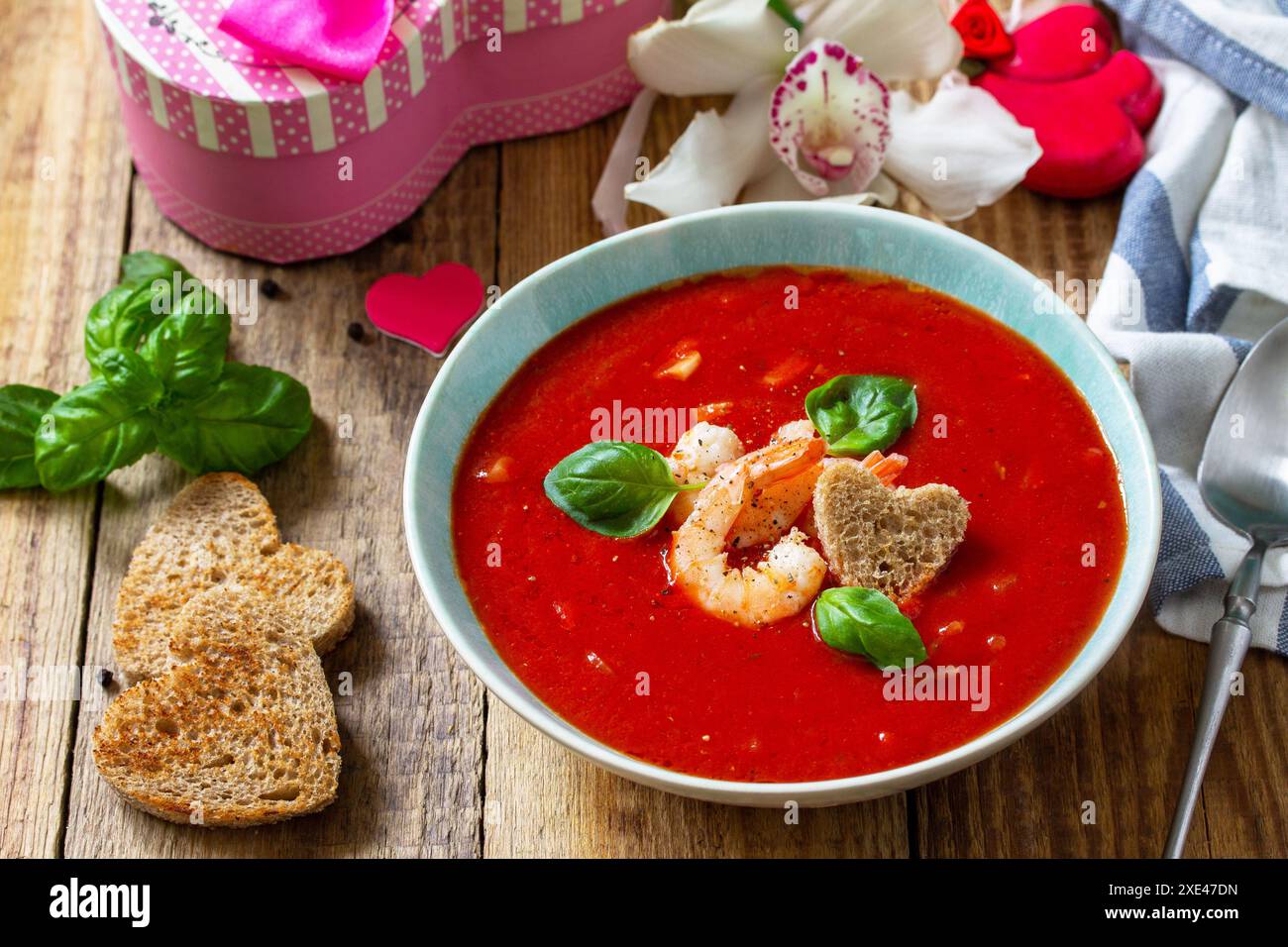 Soupe de Saint-Valentin maison, repas de fête.Soupe de tomates, purée de gazpacho avec tomates, fruits de mer servis sur une table rustique en bois. Banque D'Images