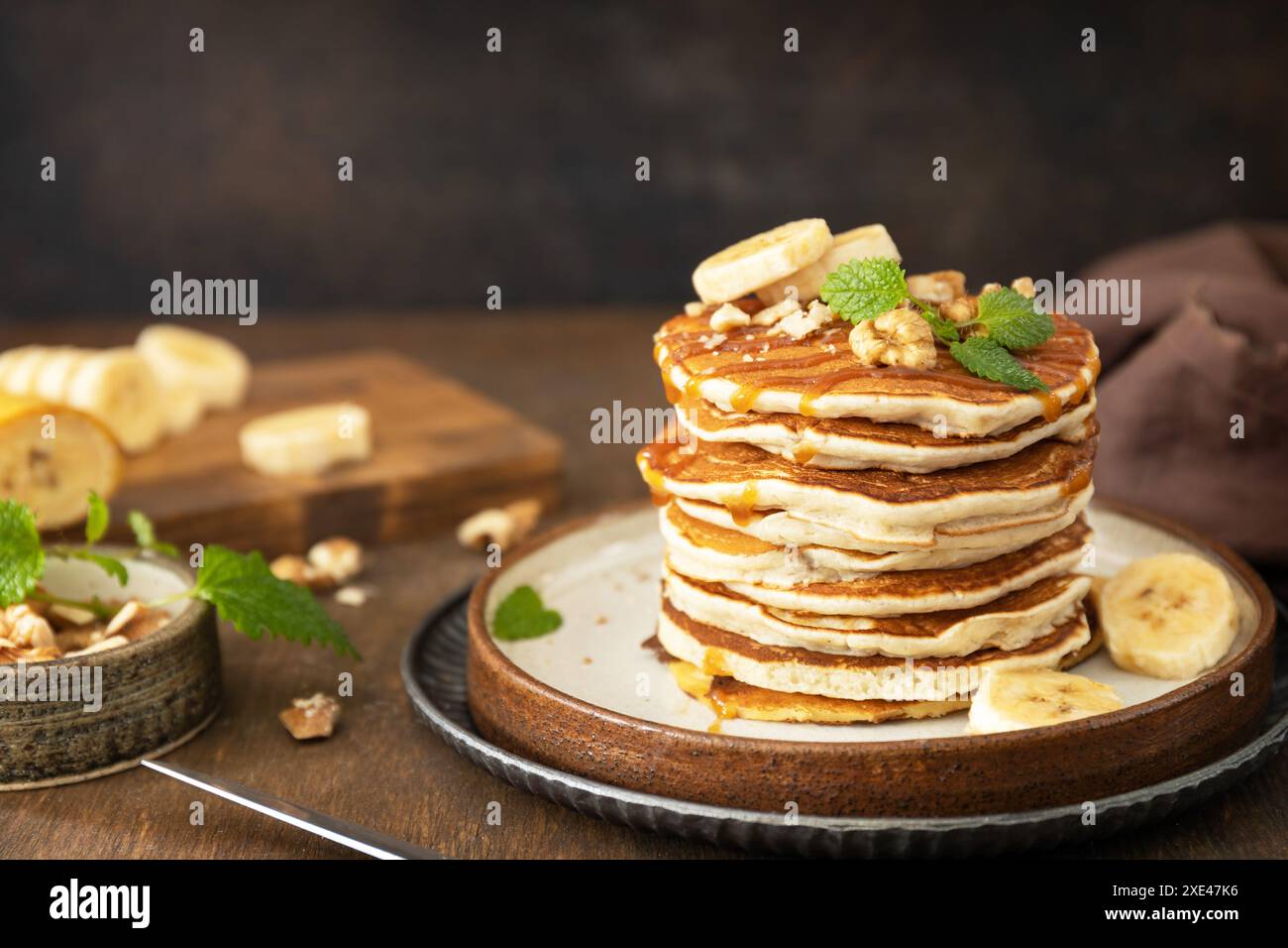 Célébration de la journée des crêpes, petit déjeuner américain. Délicieuses crêpes à la banane maison avec des noix et du caramel sur une table en bois rustique. Co Banque D'Images