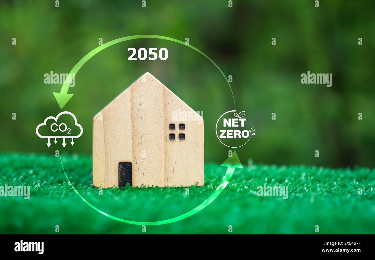 Un modèle de maison en bois sur un fond vert et une icône de symbole de réduction de dioxyde de carbone, crédit carbone, zéro net, concept de réduction des émissions de CO2, propre Banque D'Images