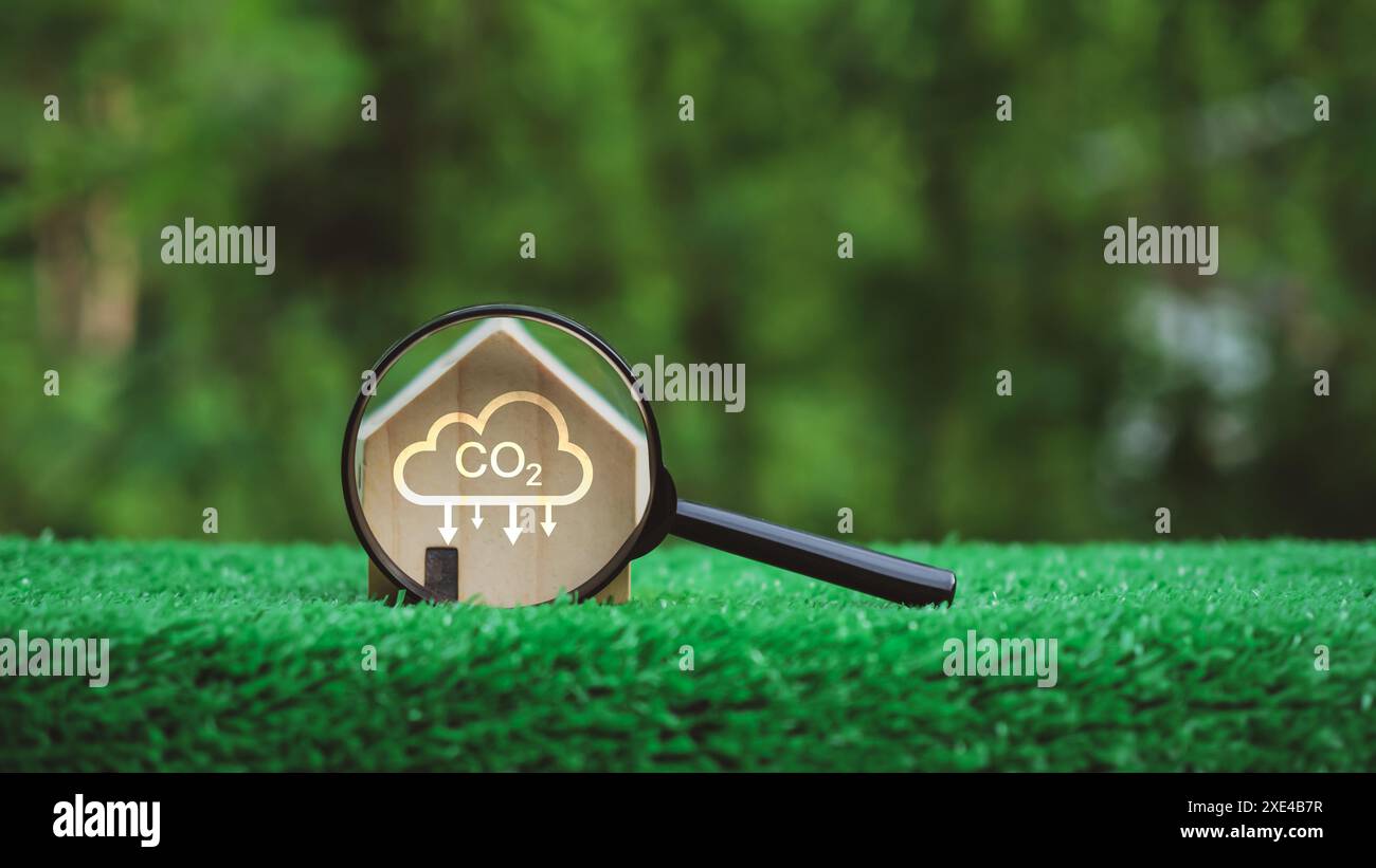 Une loupe est placée sur un champ vert herbeux avec une maison et un nuage de CO2 au premier plan, Net Zero. Concept de réduction des émissions de CO2, Clean e Banque D'Images