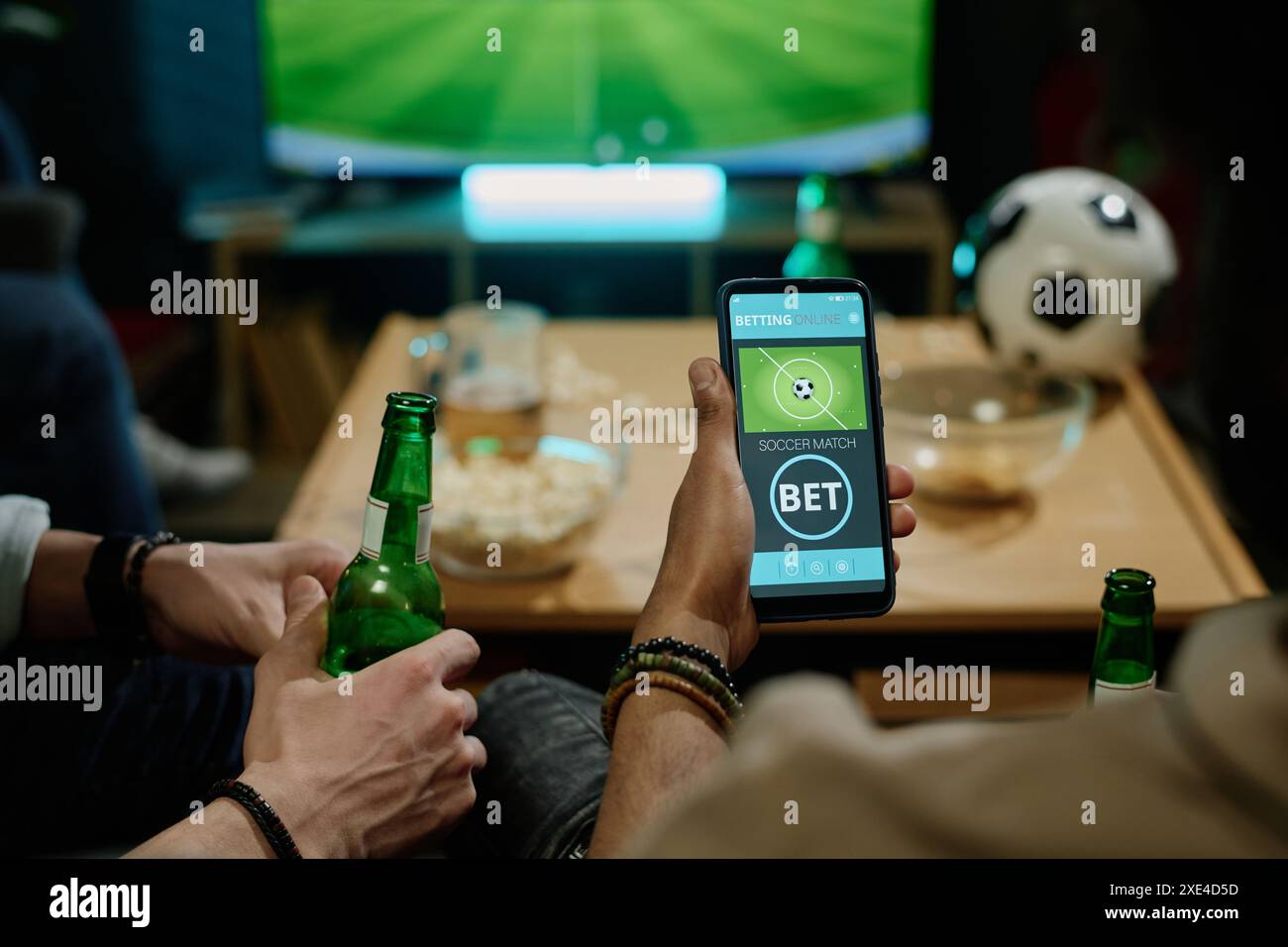 Homme méconnaissable passant du temps avec des amis regardant un match de football à la télévision et pariant sur l'équipe préférée dans l'application sur smartphone Banque D'Images