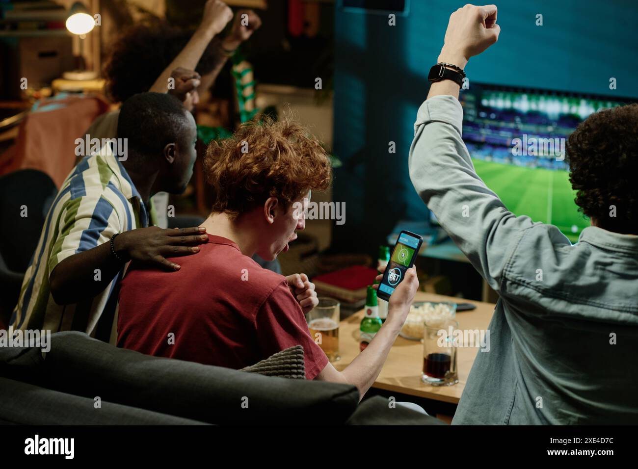 Groupe de fans de football multiethniques joyeux appréciant de regarder le match en direct à la télévision tard dans la soirée Banque D'Images