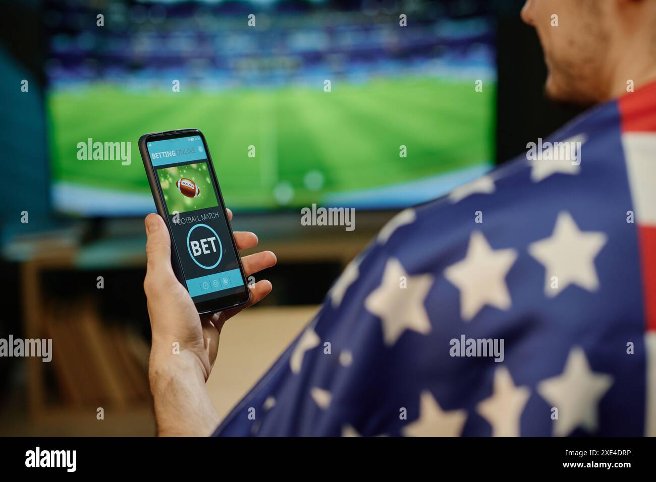 Sur le tir d'épaule de l'homme méconnaissable regardant le match de football parier sur l'équipe préférée dans l'application sur smartphone Banque D'Images