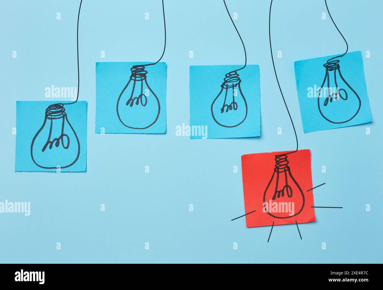 Ampoules électriques dessinées sur des feuilles de papier avec un fond bleu, signifiant le concept de la recherche de nouvelles idées. Banque D'Images