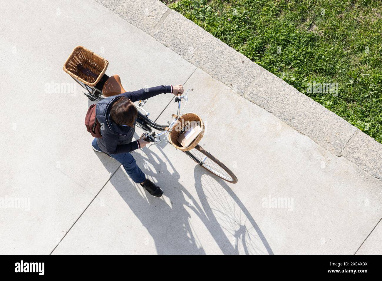 Femme marchant avec son vélo équipé de paniers pour transporter des objets. Style urbain de vie saine. Vue de dessus Banque D'Images