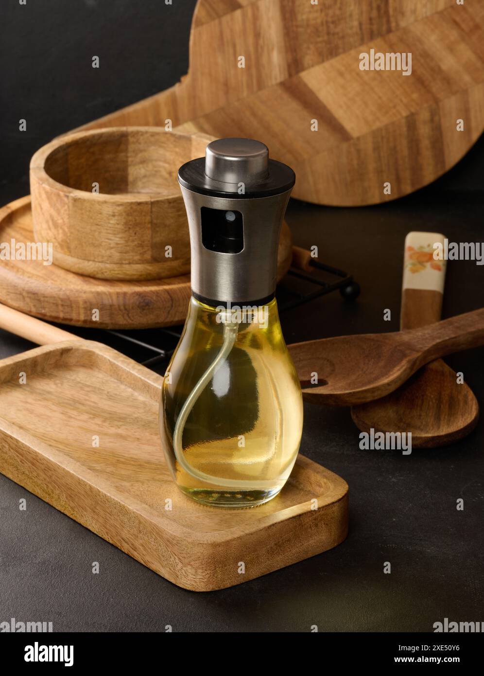 Flacon pulvérisateur transparent en verre rempli d'huile de tournesol sur une table noire Banque D'Images