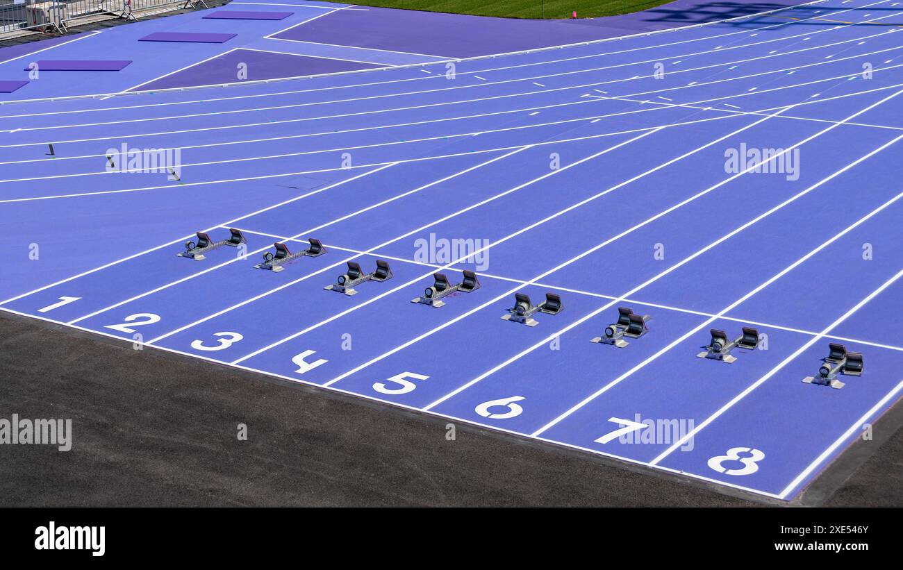 Ligne de départ d'une course de sprint avec huit voies équipées de blocs de départ sur une piste de course d'athlétisme violet synthétique Banque D'Images