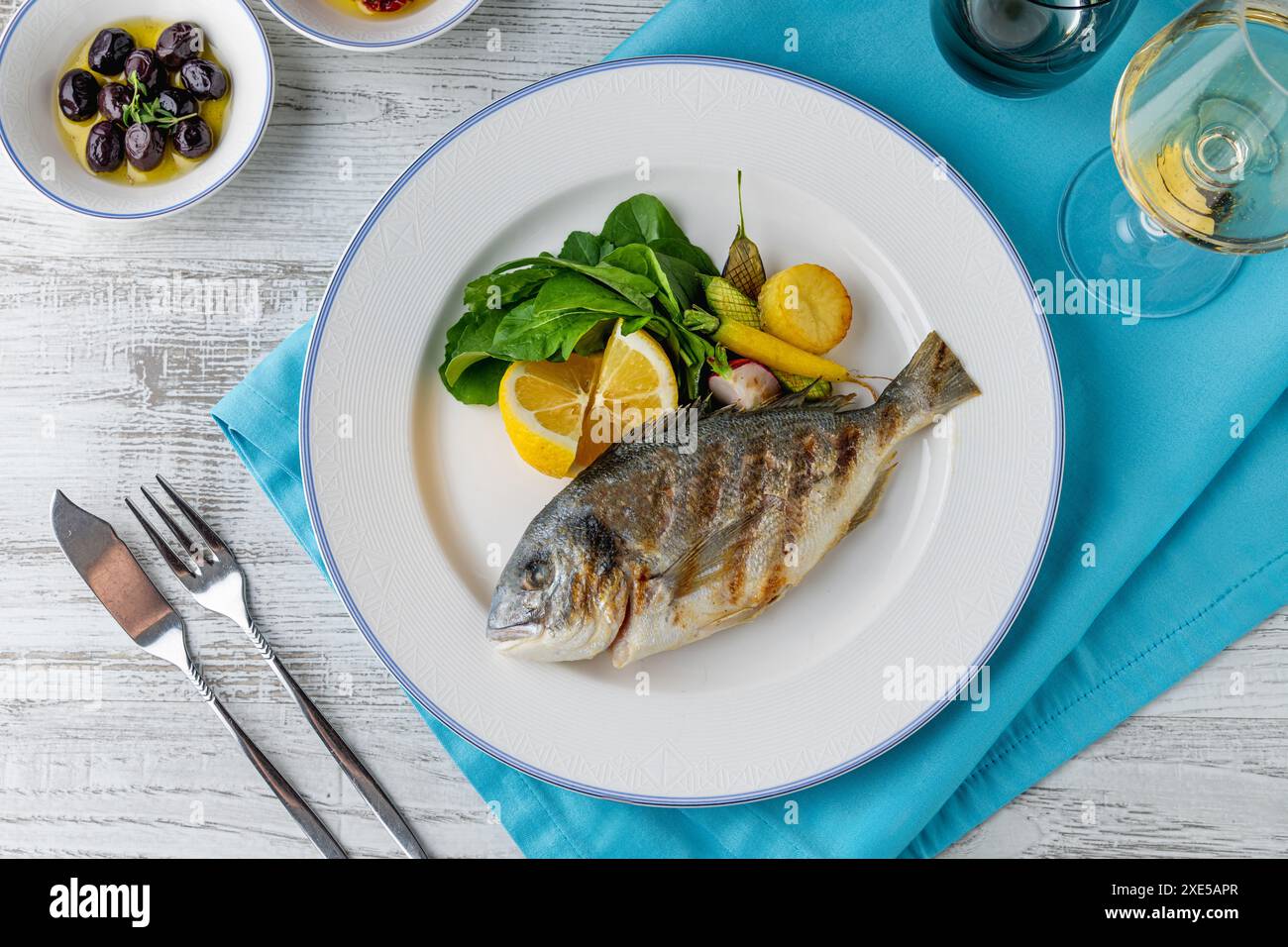 Dorade grillée avec légumes et légumes verts sur une table en bois Banque D'Images