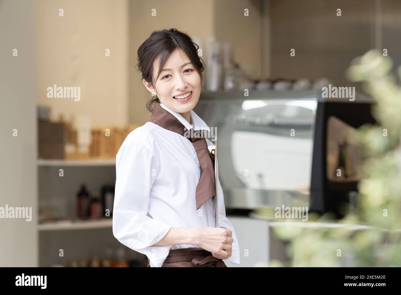 Femme souriant à la vitrine d'un café Banque D'Images