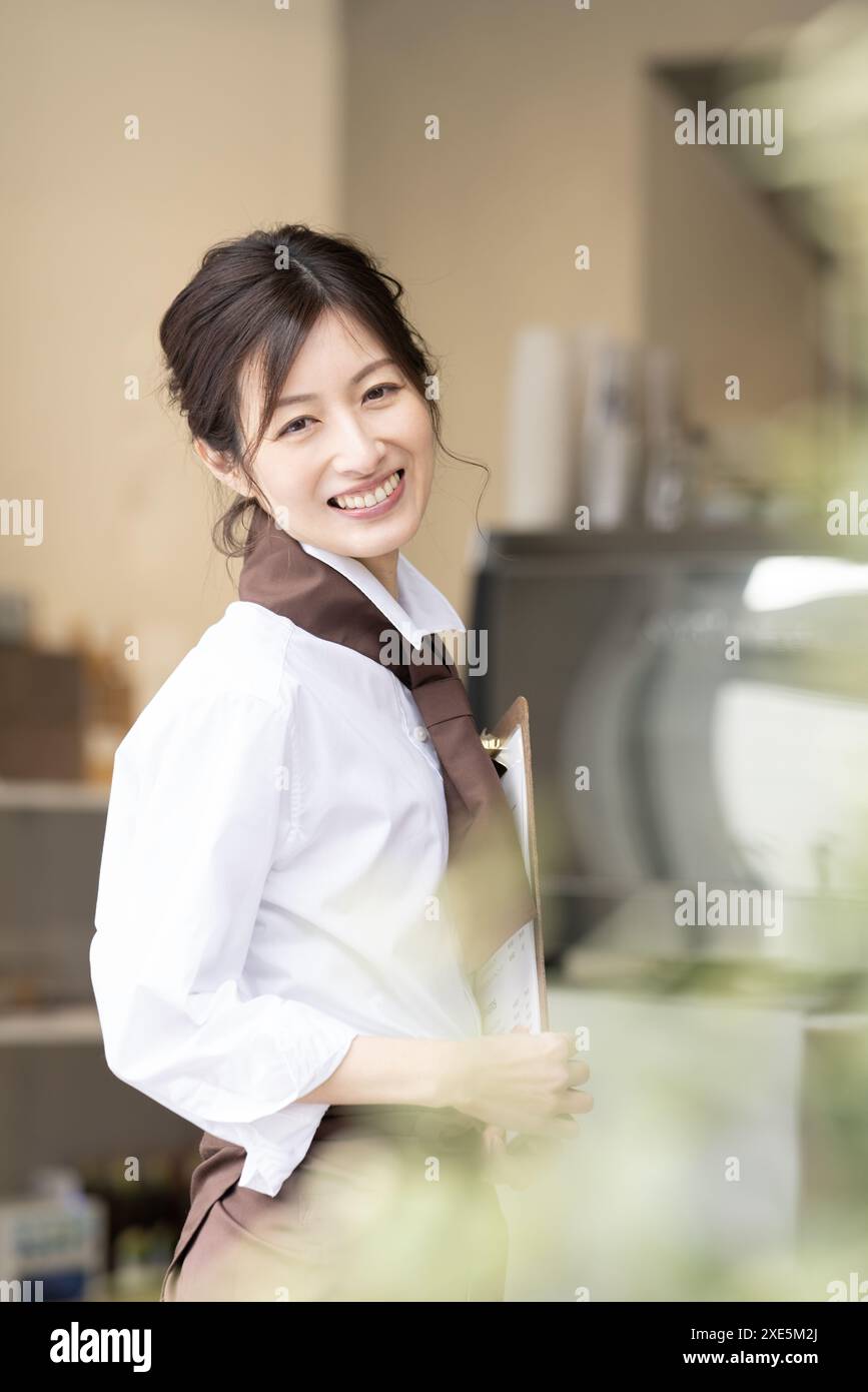 Femme souriant à la vitrine d'un café Banque D'Images