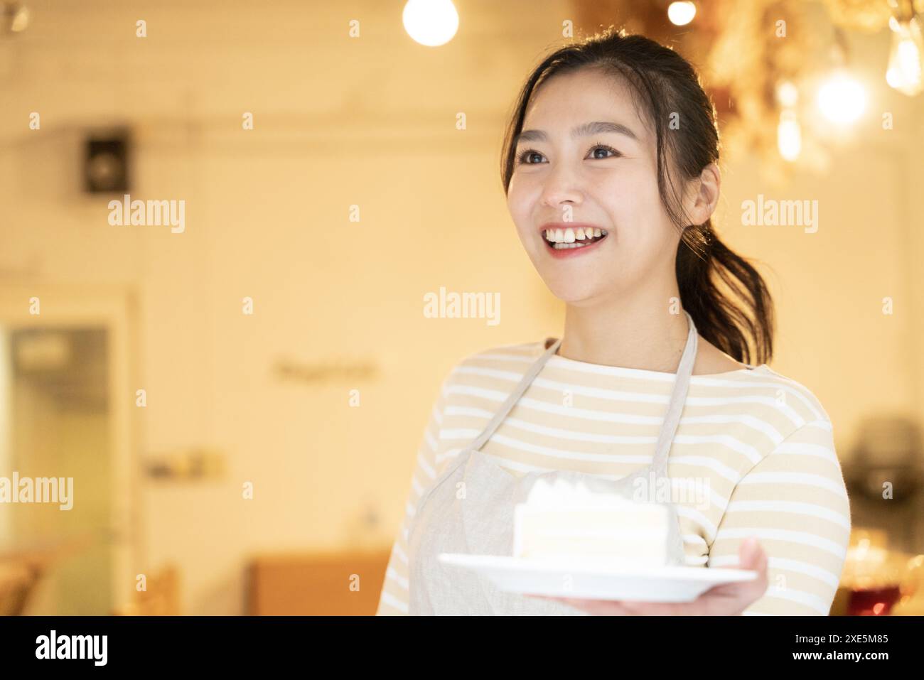 Serveuse tenant un gâteau dans un café Banque D'Images