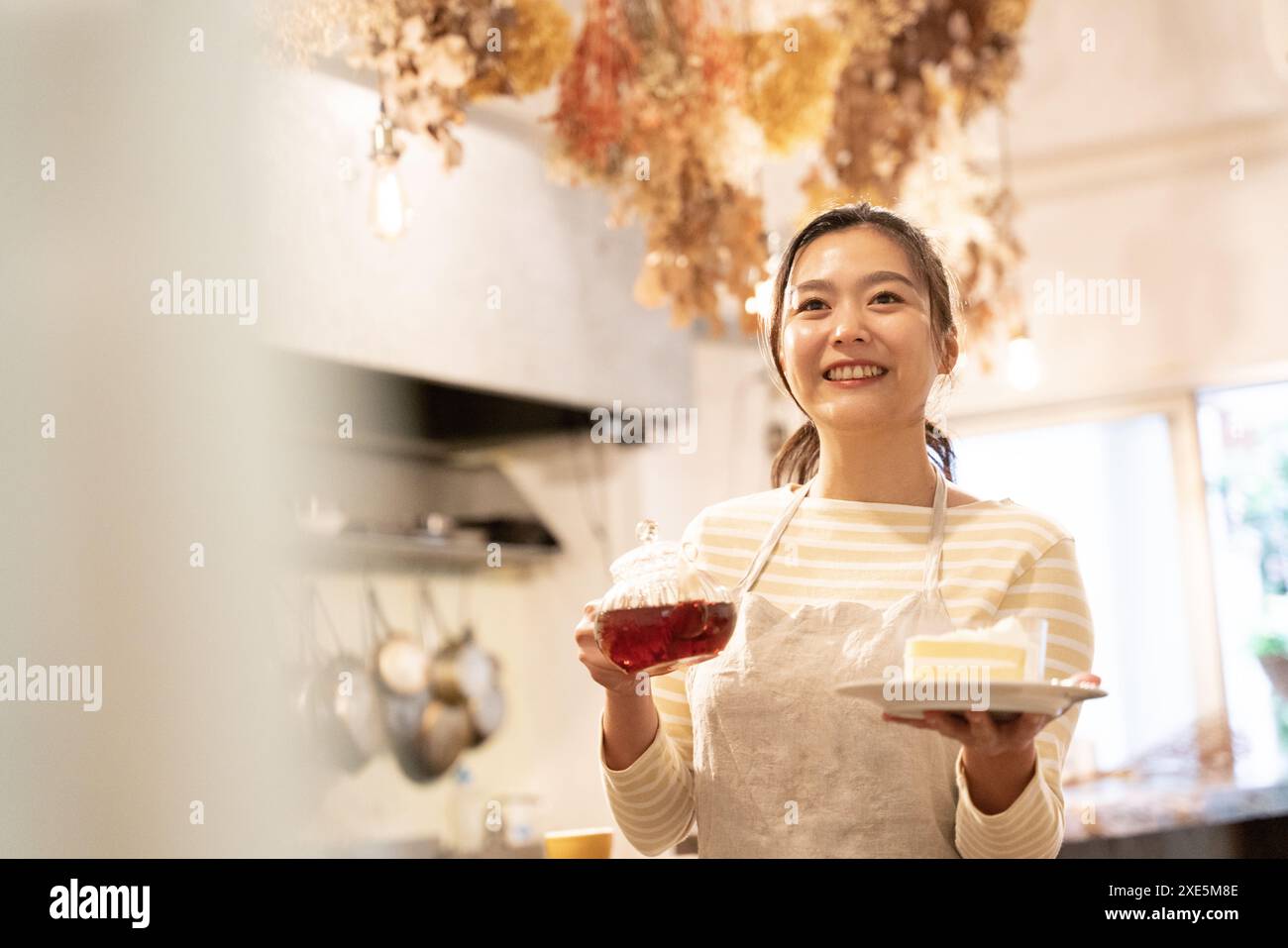 Serveuse tenant une théière et un gâteau au café Banque D'Images