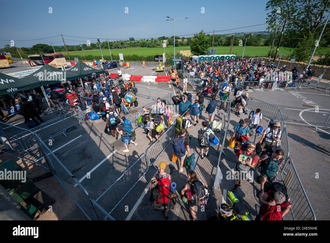 Les fêtards arrivent à la gare de Castle Cary alors qu'ils sortent de la plate-forme et prennent les bus qui les fermeront vers Glastonbury Festival à Worthy Farm dans le Somerset. Date de la photo : mercredi 26 juin 2024. Banque D'Images