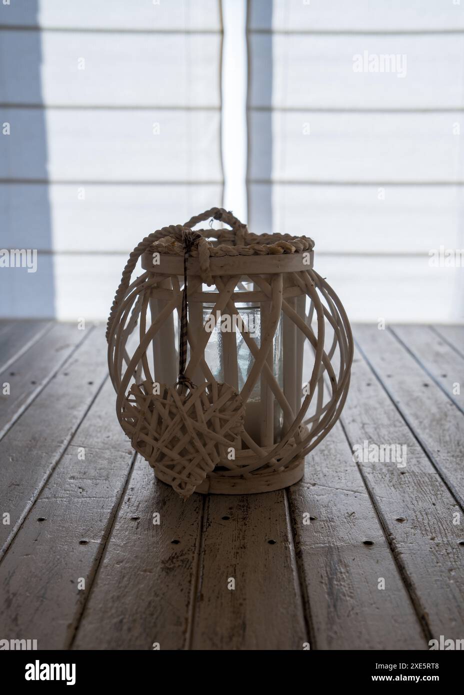 Un chandelier en bois d'osier avec un cœur se tient sur une table en bois contre un mur en bois blanc. Décoration de table, décoration Banque D'Images