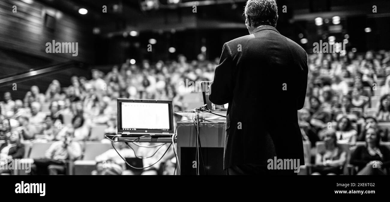 Conférencier donnant une conférence sur la conférence d'affaires d'entreprise. Personnes méconnaissables dans le public à la salle de conférence. Événement d'affaires et d'entrepreneuriat. Image en noir et blanc. Banque D'Images