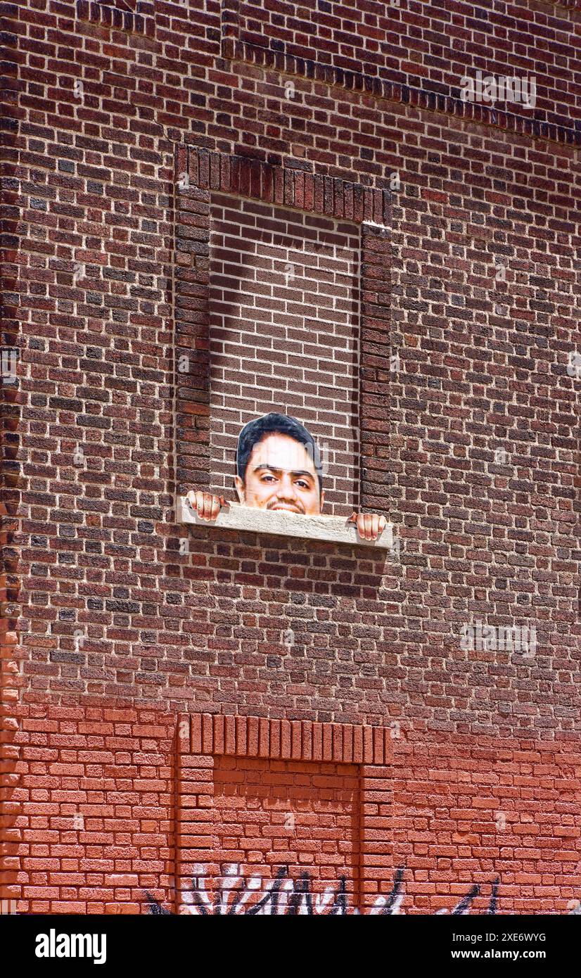 NYC Chinatown : des pairs humoristiques découpés d'une fenêtre en briques au 72-80 Henry Street, un établissement du Département de l'assainissement sous le pont de Manhattan. Banque D'Images