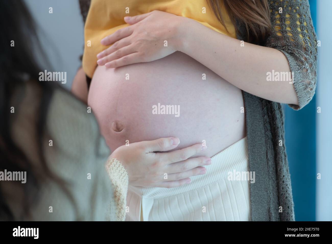 Tous les deux de la jeune mère attendant tenant bébé dans le ventre enceinte. Maternité prénatale et concept de grossesse féminine. Banque D'Images