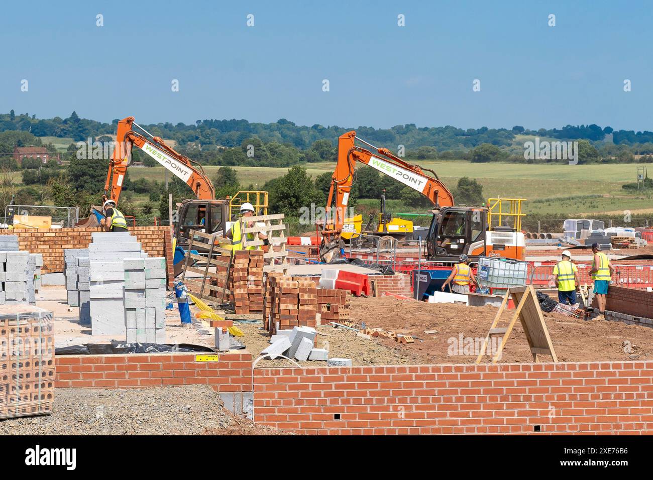 Kidderminster, Royaume-Uni. 26 juin 2024. Météo britannique : les travailleurs de la construction qui construisent de nouvelles maisons à Kidderminster sont toujours dehors sous le soleil de midi. Avec des températures atteignant 27 degrés, les travailleurs greffent dur sous le soleil d'été, dans des conditions poussiéreuses et humides l'un des jours les plus chauds de l'année. Crédit : Lee Hudson/Alamy Live News Banque D'Images