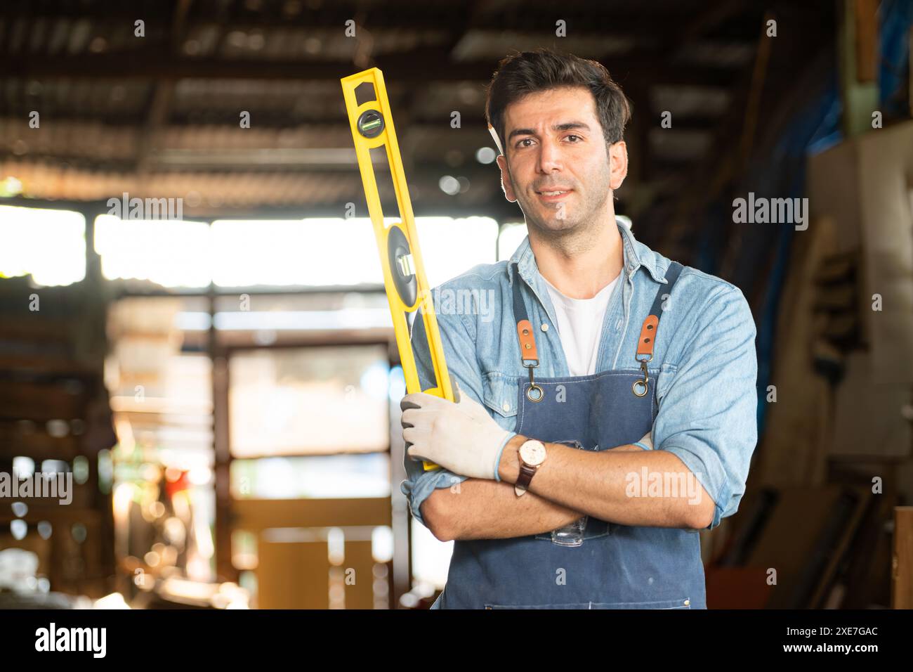 Portrait d'un charpentier tenant un niveau à bulle dans son atelier. Banque D'Images