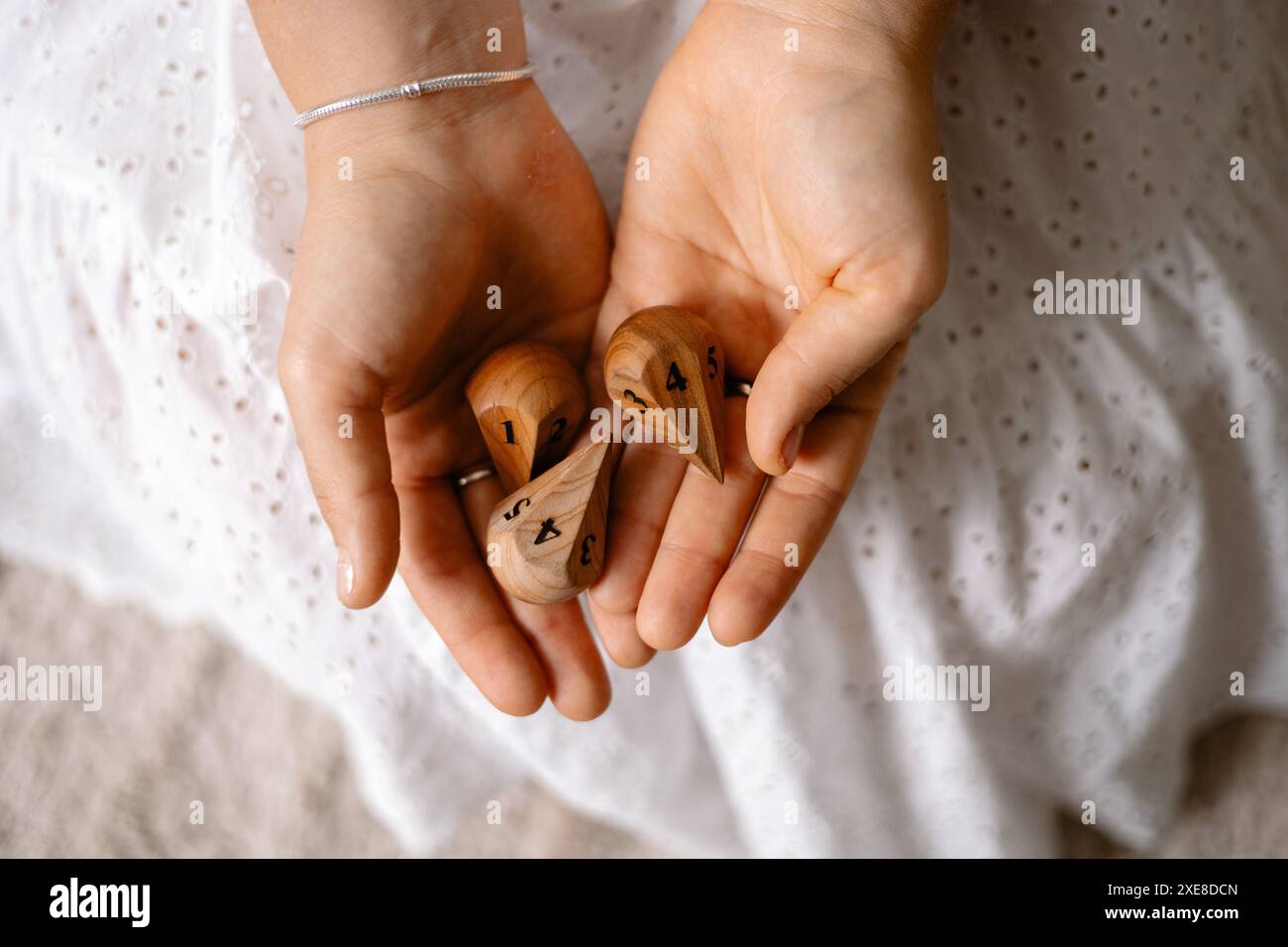 dés en bois avec des chiffres dans les mains d'une fille Banque D'Images