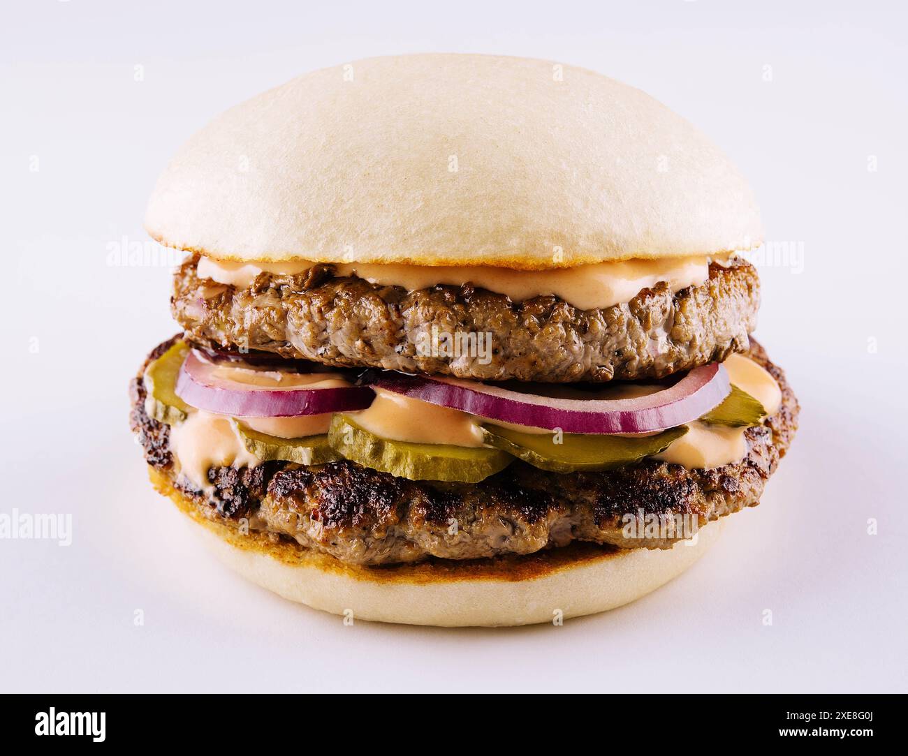 Hamburger avec deux côtelettes, concombres marinés et fromage fondu Banque D'Images