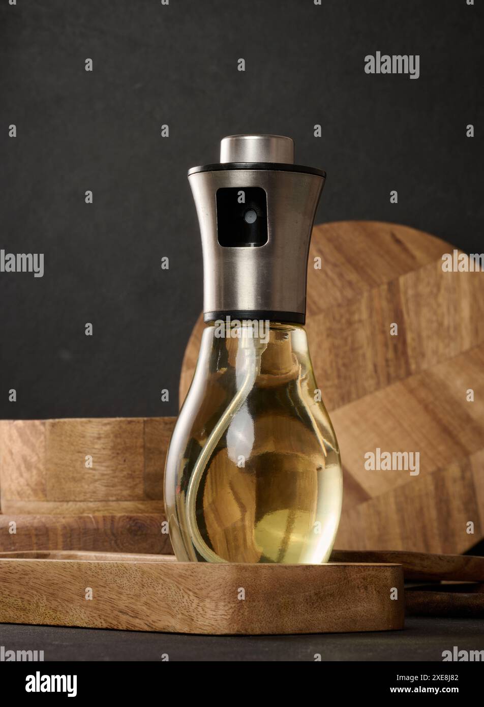 Flacon pulvérisateur transparent en verre rempli d'huile de tournesol sur une table noire Banque D'Images