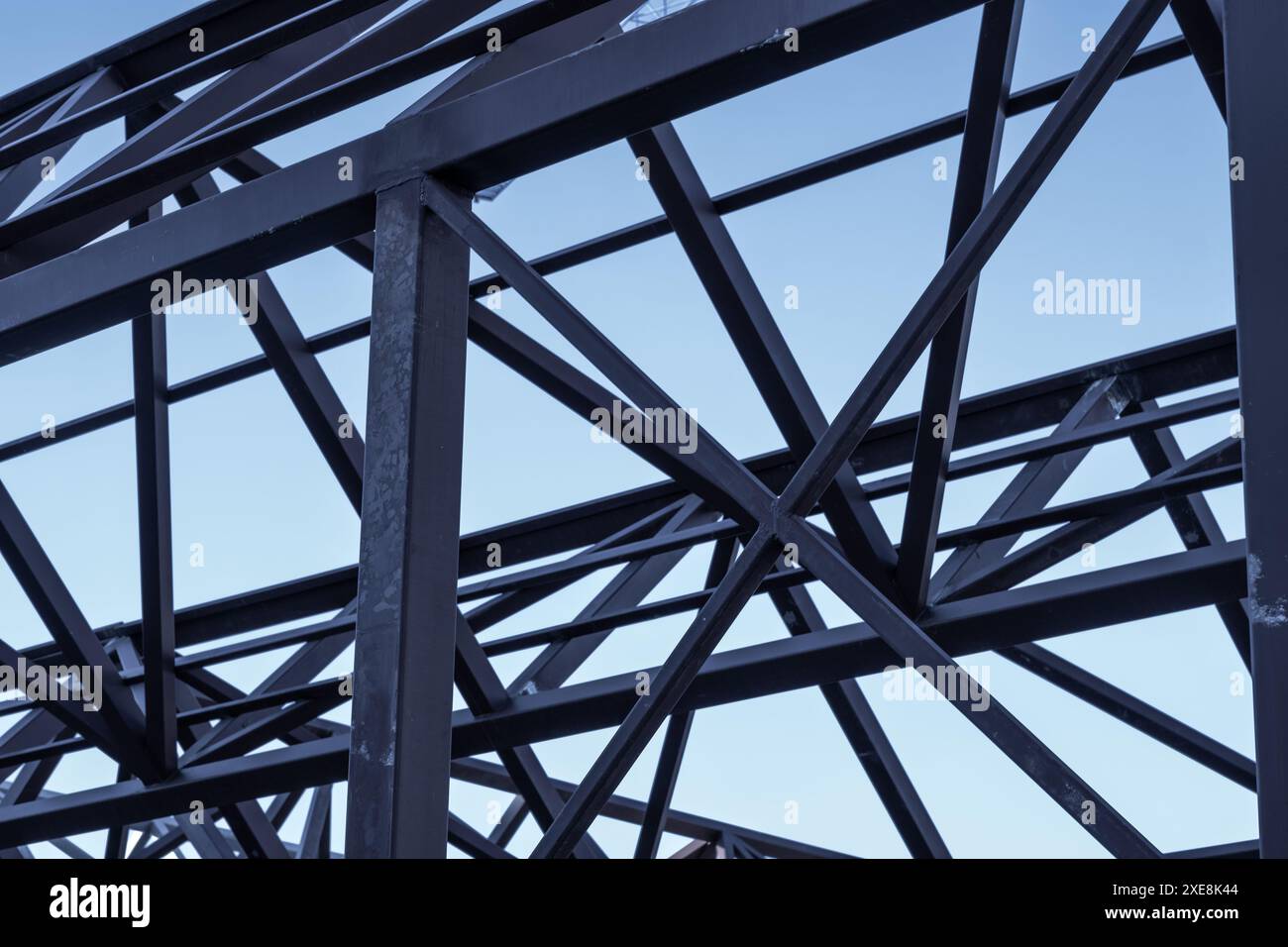 Détail de poutres en métal foncé et d'une grue bleue dans une construction moderne contre un ciel bleu foncé. Banque D'Images