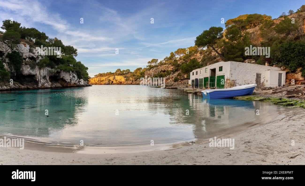 Crique idyllique et plage à Cala Pi avec le hangar à bateaux dans la lumière chaude du matin Banque D'Images