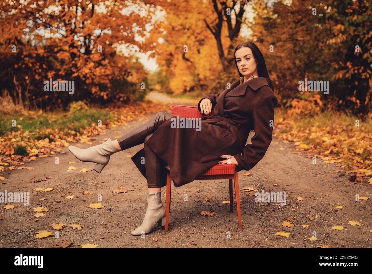 Portrait d'une jeune femme avec un vieux fauteuil dans un manteau brun en automne Banque D'Images