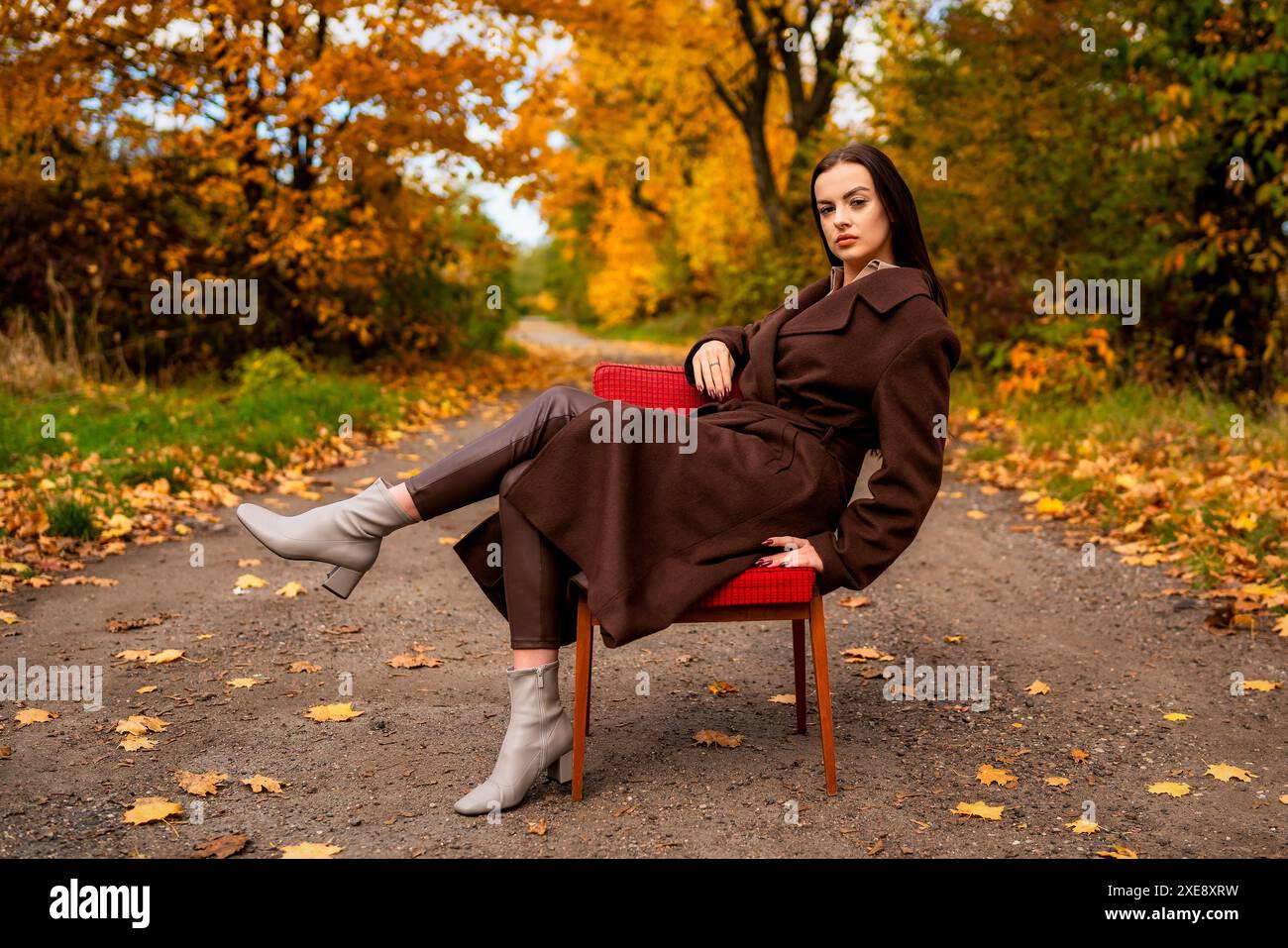 Portrait d'une jeune femme avec un vieux fauteuil dans un manteau brun en automne Banque D'Images