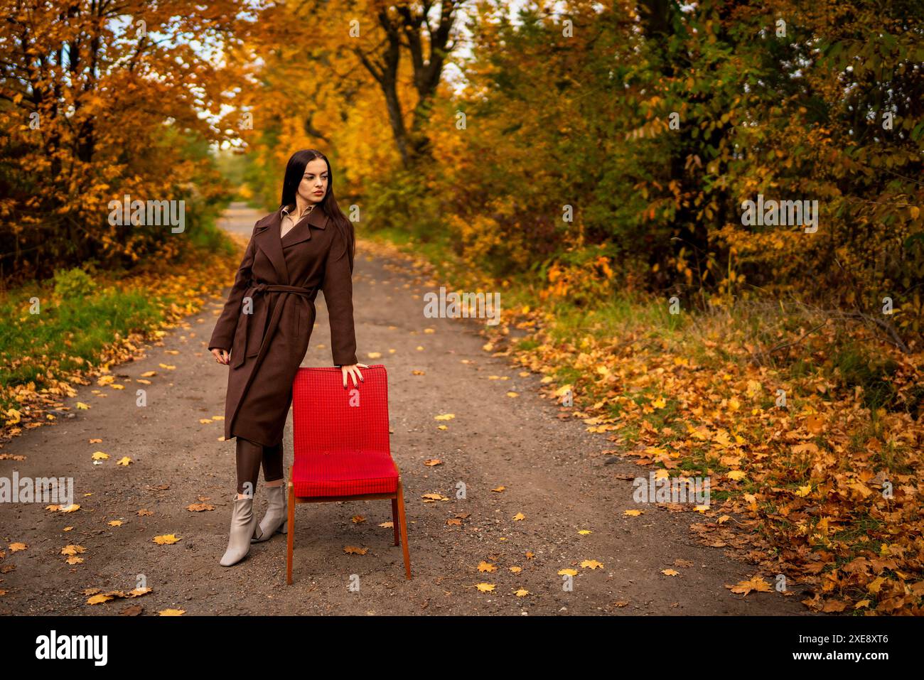 Portrait d'une jeune femme avec un vieux fauteuil dans un manteau brun en automne Banque D'Images