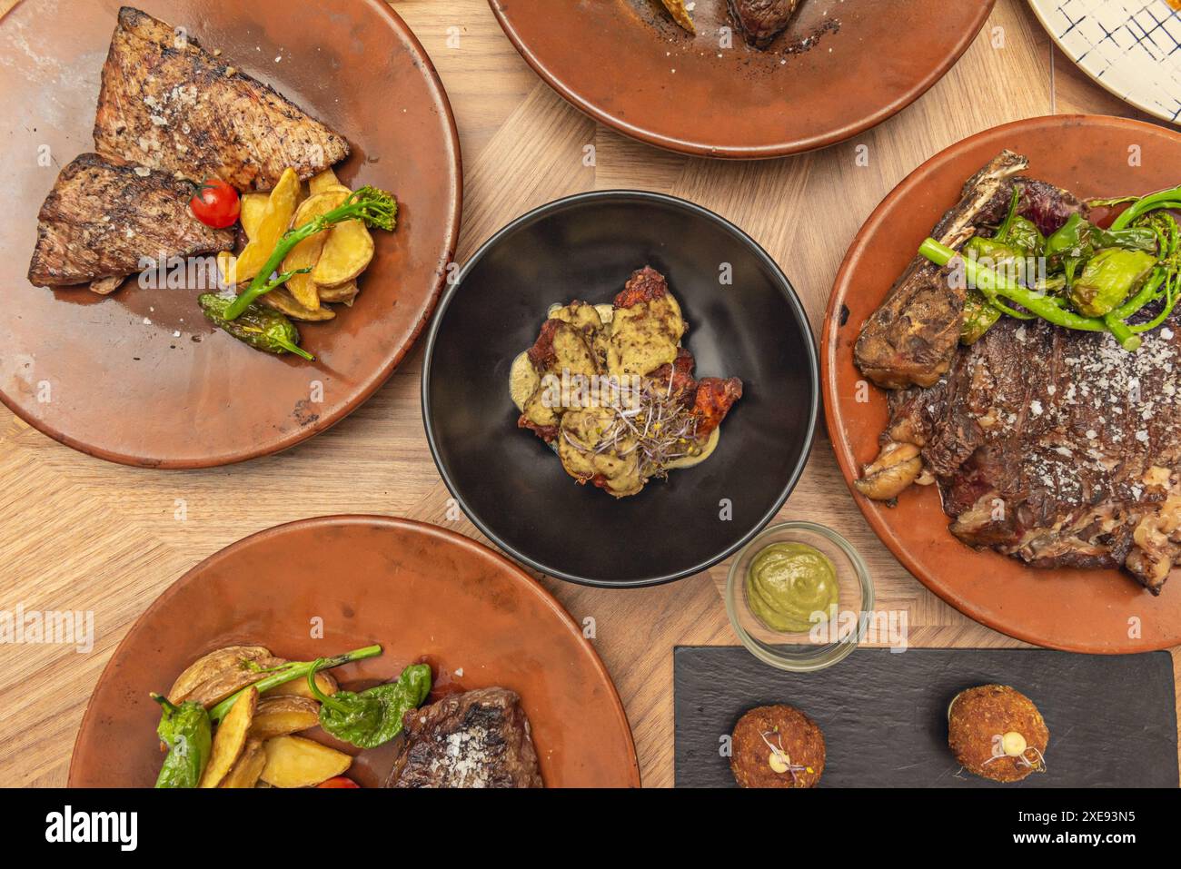 Image vue de dessus de diverses assiettes de différentes coupes de bœuf grillé avec ailes de barbecue en sauce Banque D'Images