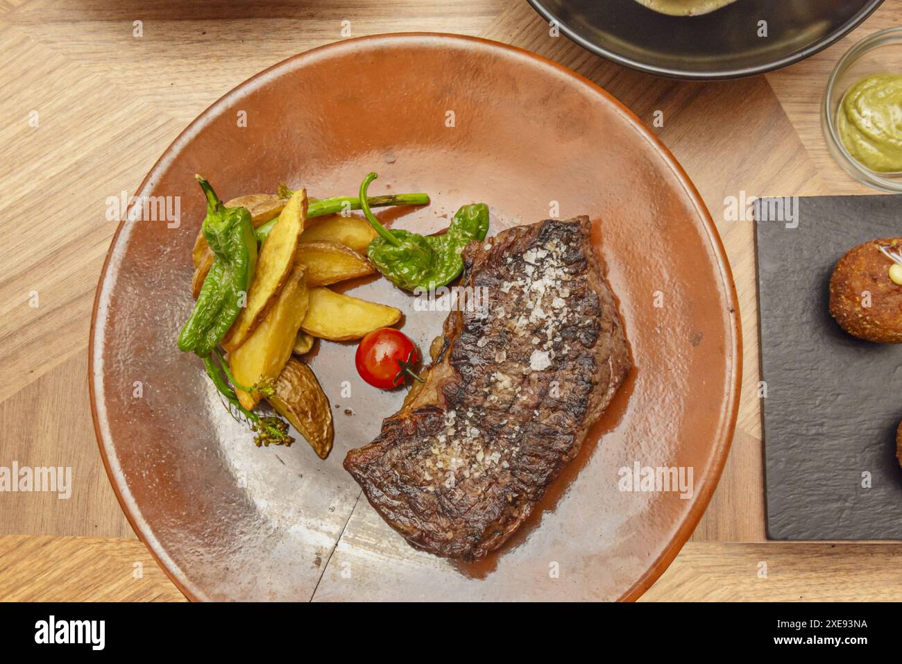 Un morceau de viande grillée avec un côté de frites et de poivrons verts rôtis Banque D'Images