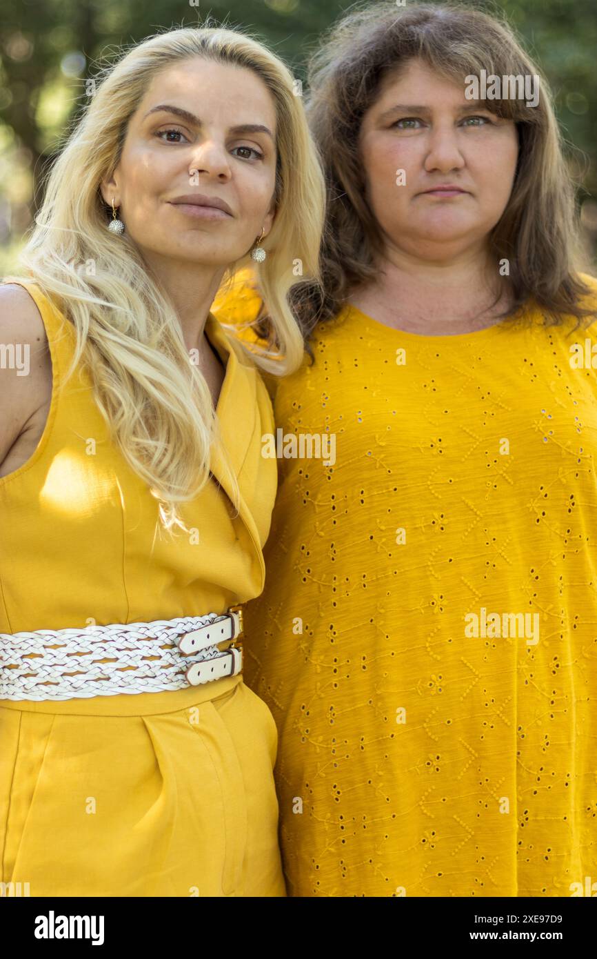 Cette image capture magnifiquement deux femmes blondes habillées de jaune, rayonnant de chaleur et d'amitié. Banque D'Images