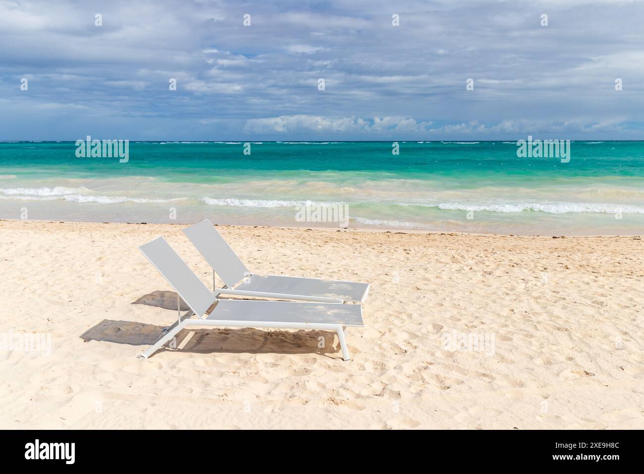 Deux chaises longues vacantes sont sur la plage par une journée ensoleillée. République dominicaine, Bavaro Beach Banque D'Images