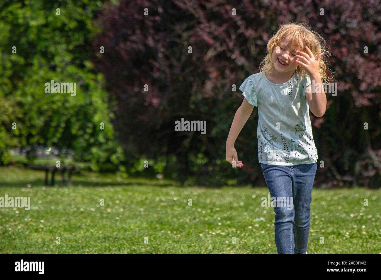 Heureuse petite fille marchant dans le parc nettoyant les cheveux mouillés du visage Banque D'Images