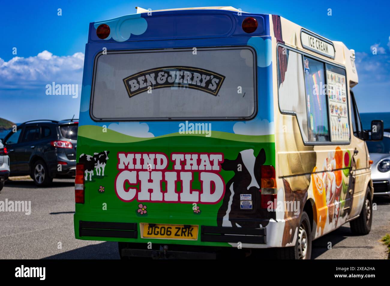 Camion de crème glacée coloré garé avec un signe d'avertissement «Mind That Child» à l'arrière sous un ciel bleu Banque D'Images