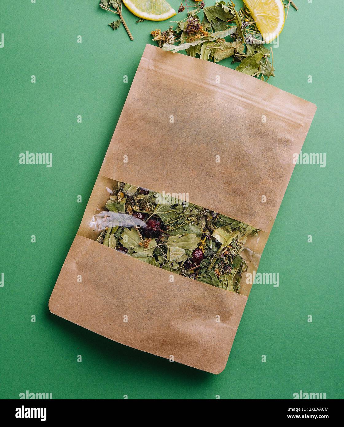 Thé en feuilles renversé hors d'un paquet de papier avec des tranches orange sur fond vert Banque D'Images Thé en feuilles renversé hors d'un paquet de papier avec des tranches orange sur fond vert Banque D'Images