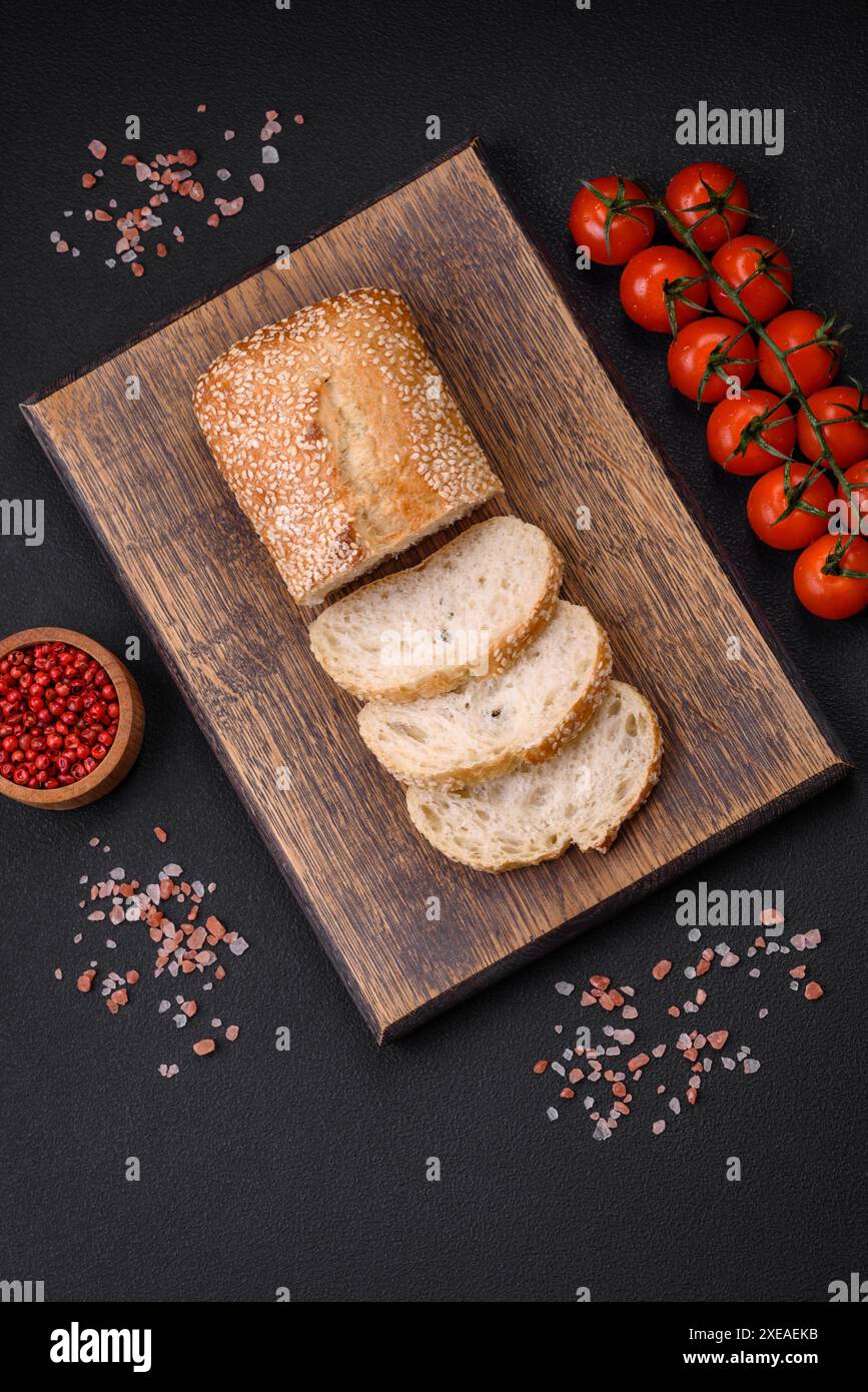 Baguette croustillante à la farine de blé avec des graines de sésame sur une planche à découper en bois Banque D'Images