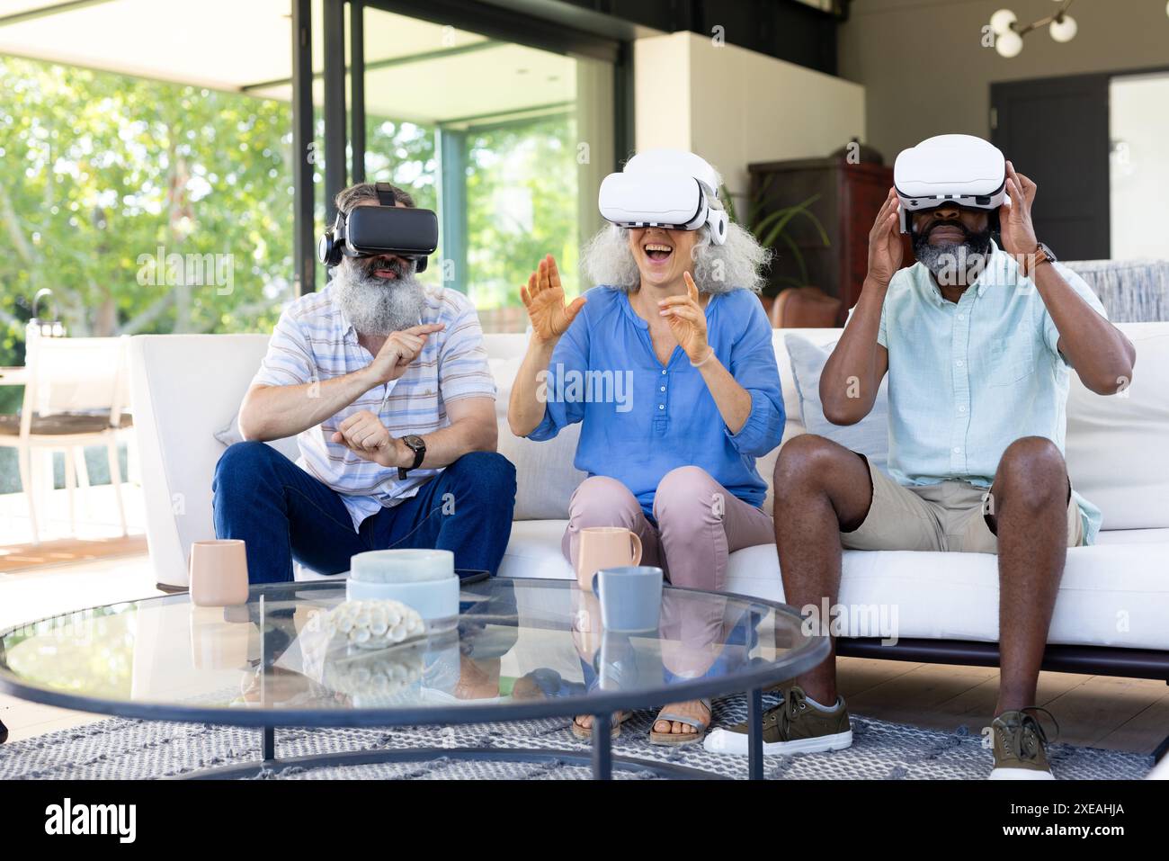À la maison, groupe diversifié de personnes âgées utilisant des casques VR, profitant de l'expérience de réalité virtuelle Banque D'Images
