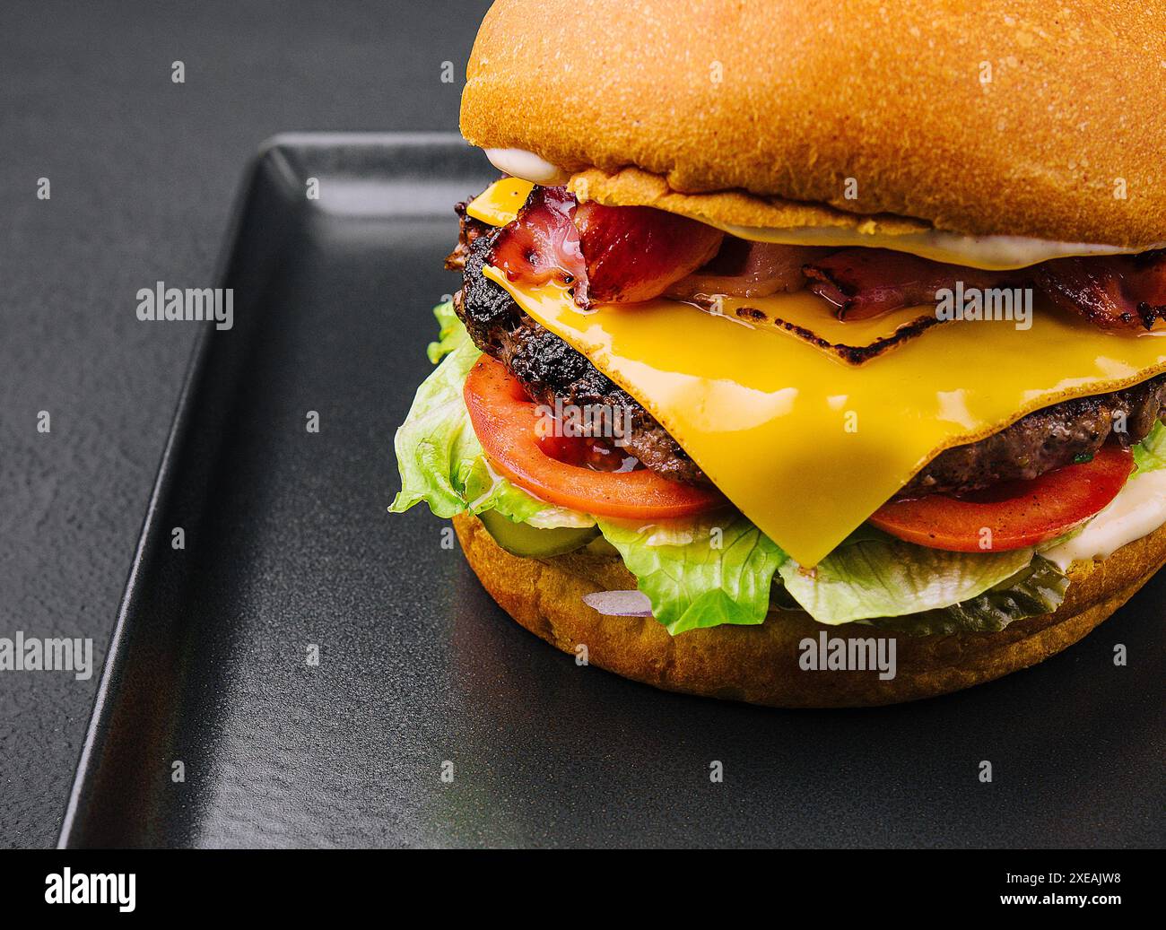 Hamburger au bacon avec patty de bœuf sur plateau noir Banque D'Images