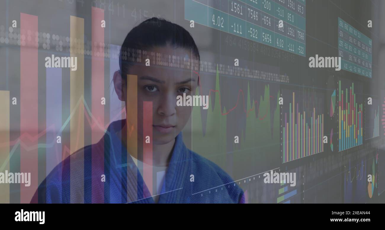 Image de graphiques et de tableaux numériques, artiste martiale biraciale sérieuse debout contre le mur Banque D'Images