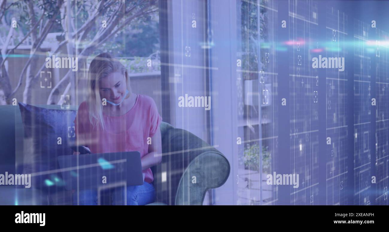 Image de traitement de données sur une femme caucasienne avec masque facial à l'aide d'un ordinateur portable Banque D'Images