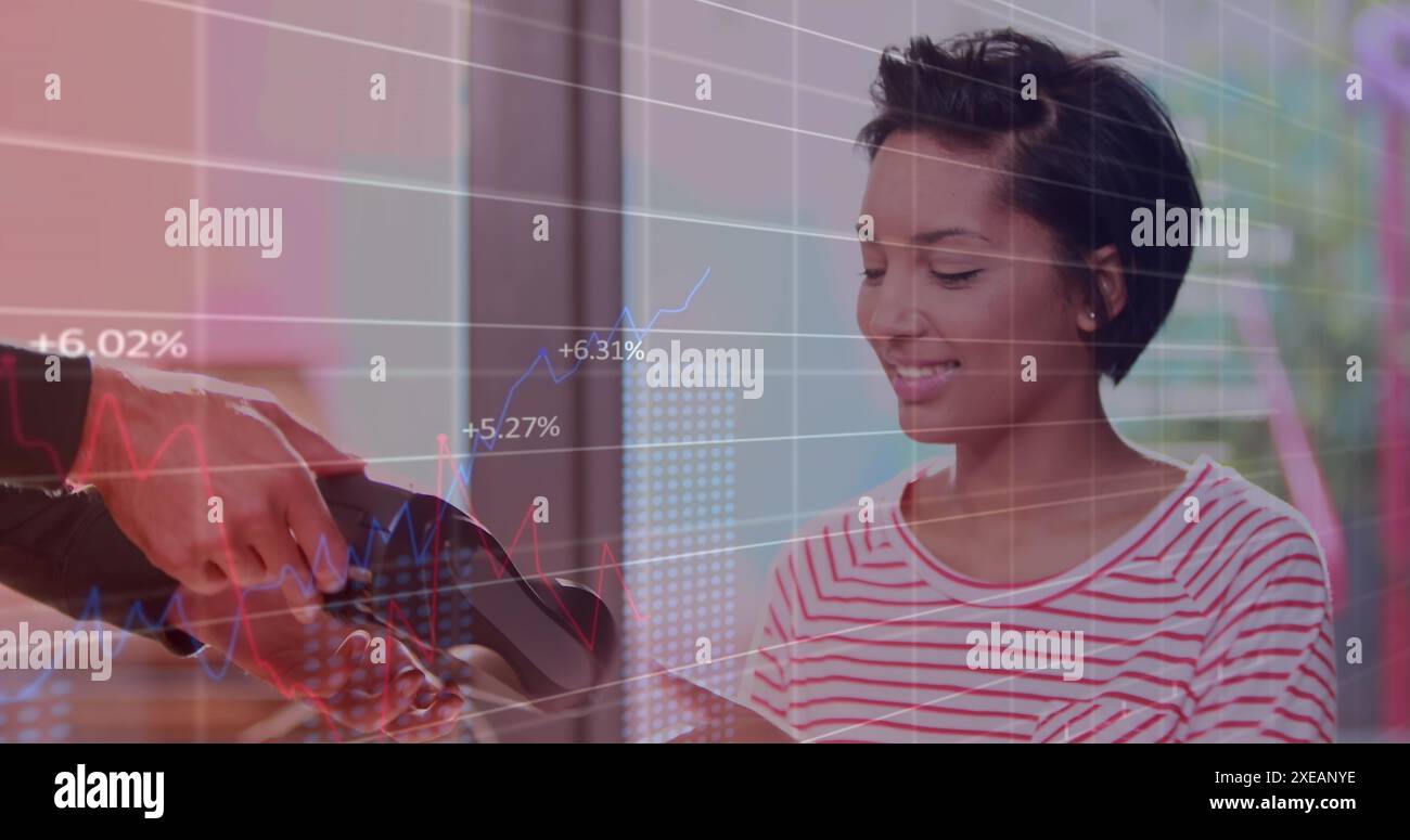 Image du traitement des données sur la femme biraciale payant dans le magasin Banque D'Images