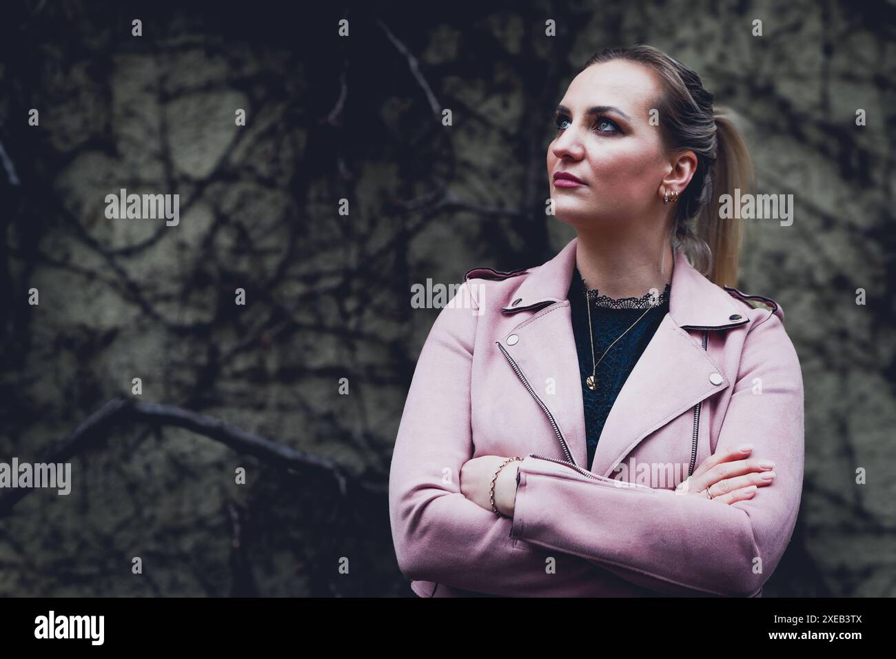 Femme dans une veste rose se tient devant un mur Banque D'Images