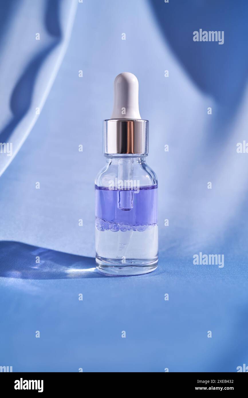 Sérum facial à deux composants sur fond de soie bleue. Banque D'Images