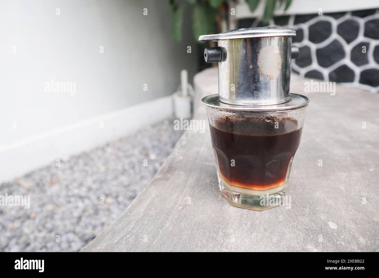 Goutte à goutte vietnamienne, café vietnamien au lait condensé dans des tasses en verre et cafetière traditionnelle en métal phin. Méthode traditionnelle de fabrication du vietname Banque D'Images