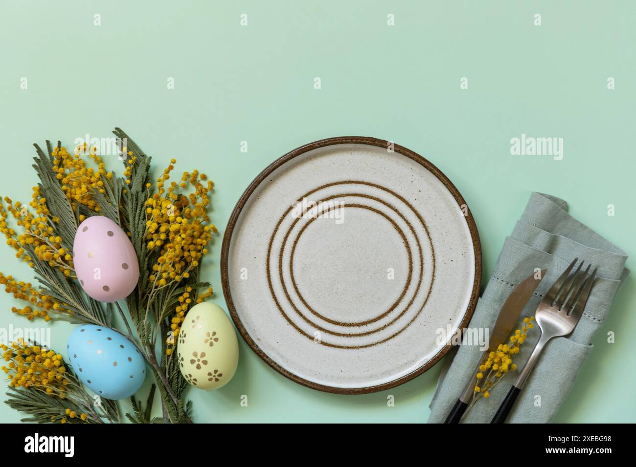 Table pour le dîner de Pâques avec œufs de pâques et mimosa sur un fond pastel. Banque D'Images