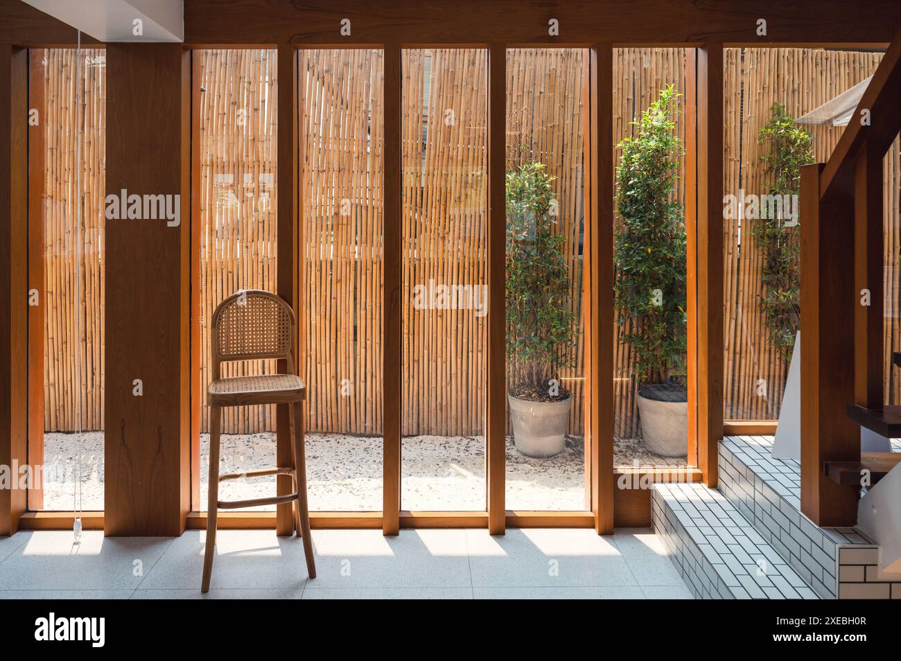 Intérieur de fenêtre en verre en bois avec chaise tissée et lumière du soleil dans maison rétro traditionnelle Banque D'Images
