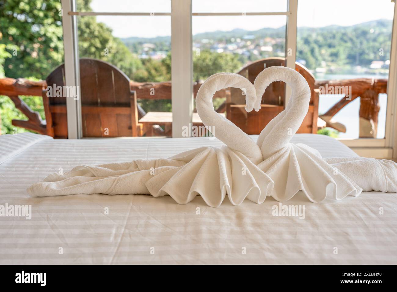 Serviettes pliées en forme de cygne de couple sur le lit de l'hôtel Banque D'Images